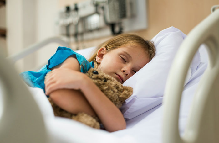 Young girl in hospital bed hugging teddy bear, illustrating child with lactose intolerance and family drama. Young girl in hospital bed hugging teddy bear, illustrating child with lactose intolerance and family drama.