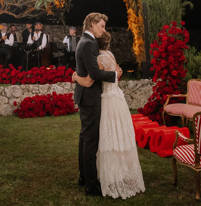 Couple embracing at a romantic outdoor event with red roses and live musicians creating a heartfelt atmosphere. Couple embracing at a romantic outdoor event with red roses and live musicians creating a heartfelt atmosphere.