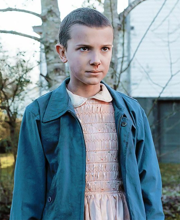 Young Millie Bobby Brown wearing a blue jacket and pink dress outdoors, linked to adoption and interview concerns. Young Millie Bobby Brown wearing a blue jacket and pink dress outdoors, linked to adoption and interview concerns.