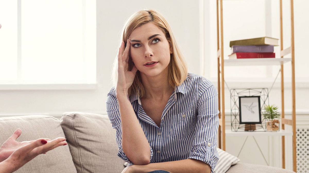 Young bride looking frustrated while discussing wedding night awkwardness with mother in a modern living room setting