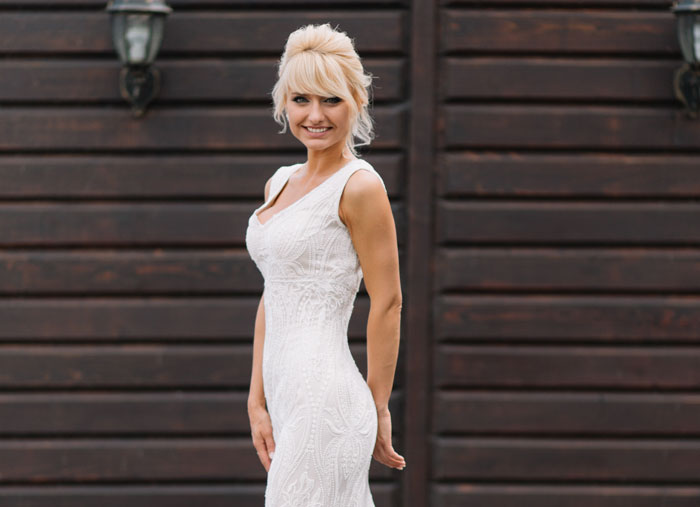 Woman wearing a white gown standing outdoors, illustrating bride's mom threatening to skip wedding over dress choice. Woman wearing a white gown standing outdoors, illustrating bride's mom threatening to skip wedding over dress choice.
