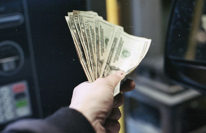 Hand holding cash in front of a vending machine representing shocking secrets revealed after someone died. Hand holding cash in front of a vending machine representing shocking secrets revealed after someone died.