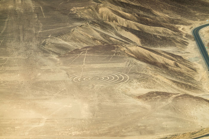 Aerial view of ancient geoglyphs etched into desert terrain, showcasing mysterious large-scale earth drawings. Aerial view of ancient geoglyphs etched into desert terrain, showcasing mysterious large-scale earth drawings.