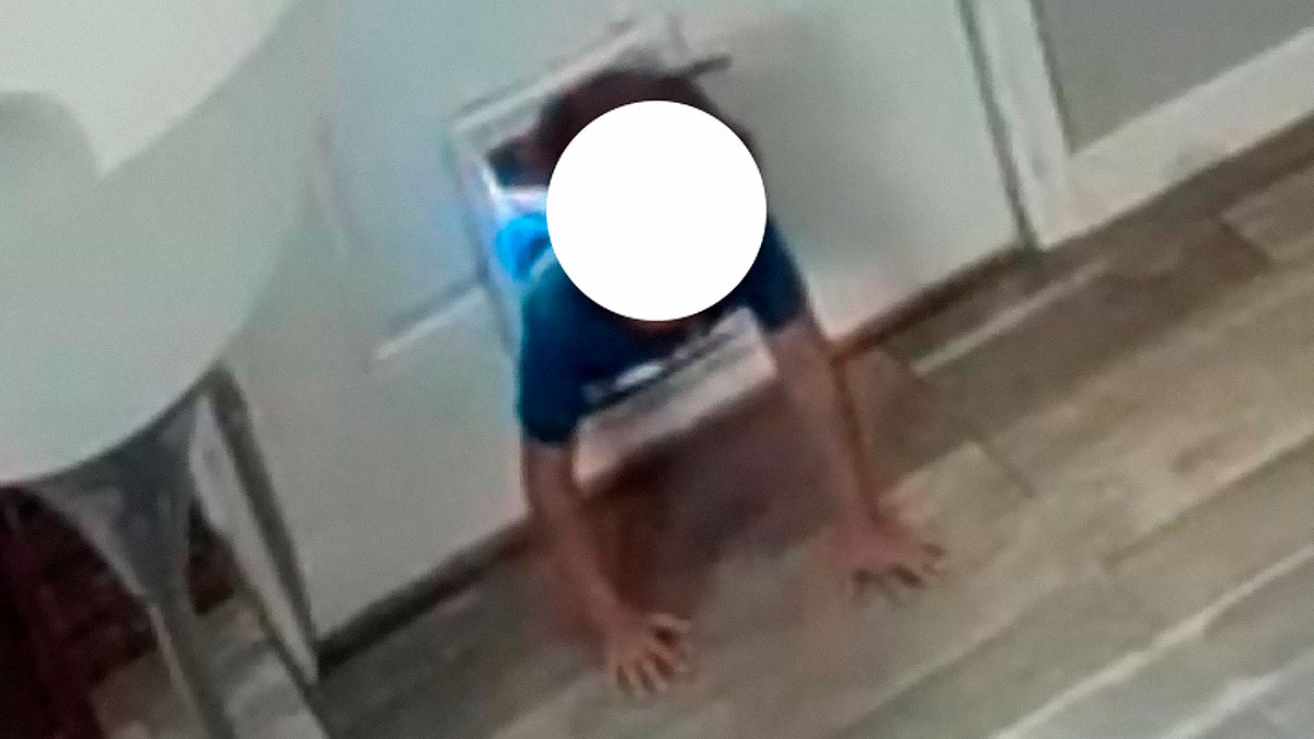 Young boy crawling through a pet door into a home, woman catches neighboru2019s son with surprised reaction visible at home entry.