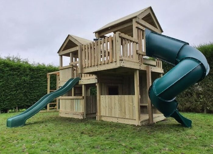 Large wooden playhouse with green slides in a backyard, highlighting privacy concerns and frustration. Large wooden playhouse with green slides in a backyard, highlighting privacy concerns and frustration.