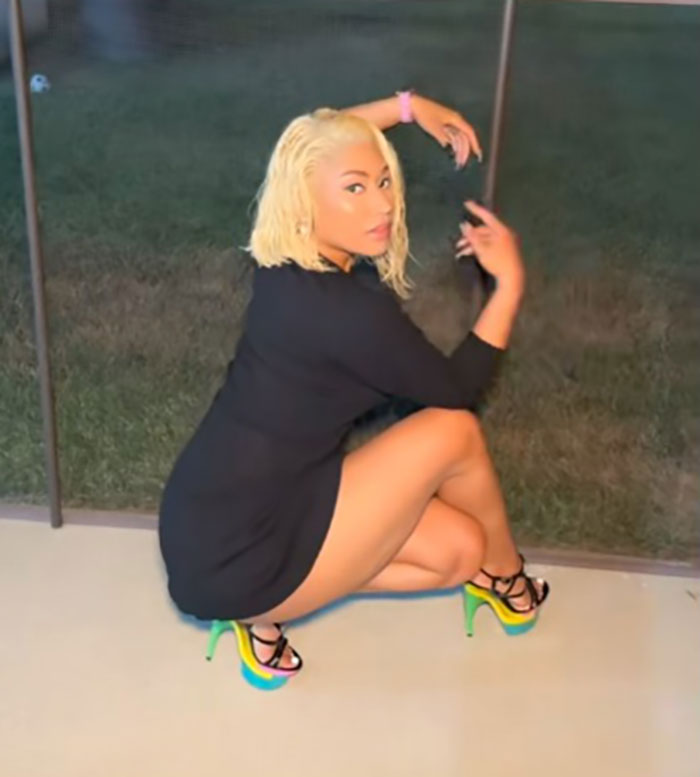 Influencer posing outdoors wearing colorful stilettos, linked to spine injury after attempting Nicki Minaj stiletto challenge. Influencer posing outdoors wearing colorful stilettos, linked to spine injury after attempting Nicki Minaj stiletto challenge.