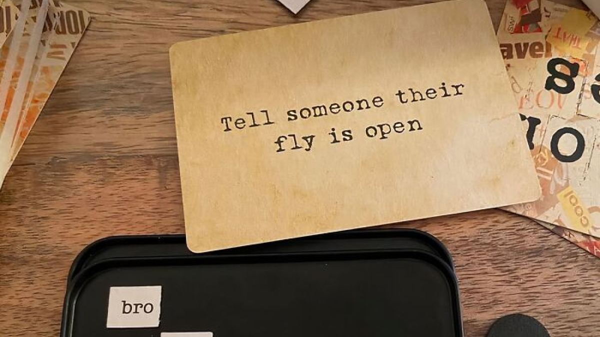Card with the phrase tell someone their fly is open on a wooden table, a quirky impulse buy product.