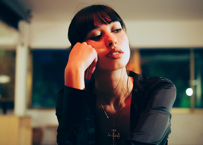 Young woman sitting indoors at night looking thoughtful, illustrating neighbor refuses tourists patio use and Airbnb discrimination. Young woman sitting indoors at night looking thoughtful, illustrating neighbor refuses tourists patio use and Airbnb discrimination.