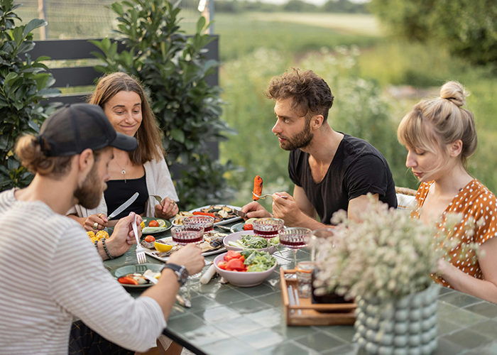 Group of tourists having a meal on a patio exterior, relating to neighbor refusing patio use and Airbnb discrimination claims. Group of tourists having a meal on a patio exterior, relating to neighbor refusing patio use and Airbnb discrimination claims.