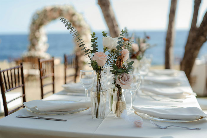 Elegant wedding venue table setup with floral centerpieces by the ocean, highlighting woman refuses to cancel dream wedding venue. Elegant wedding venue table setup with floral centerpieces by the ocean, highlighting woman refuses to cancel dream wedding venue.