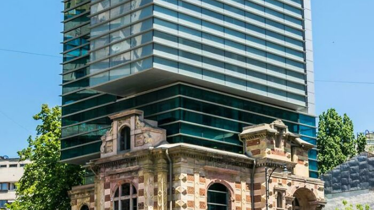 Old versus modern architecture contrast shown by a historic brick building next to a contemporary glass skyscraper.