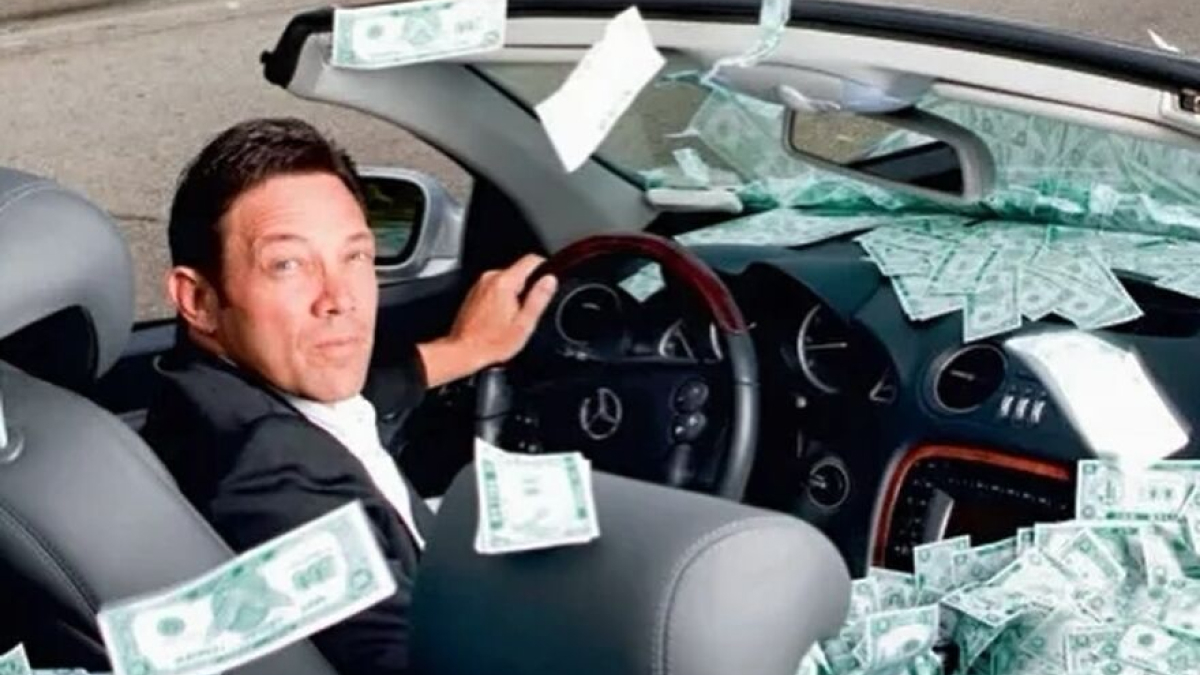 Man in a car surrounded by flying money, symbolizing Jordan Belfortu2019s financial reality and money woes in 2025.