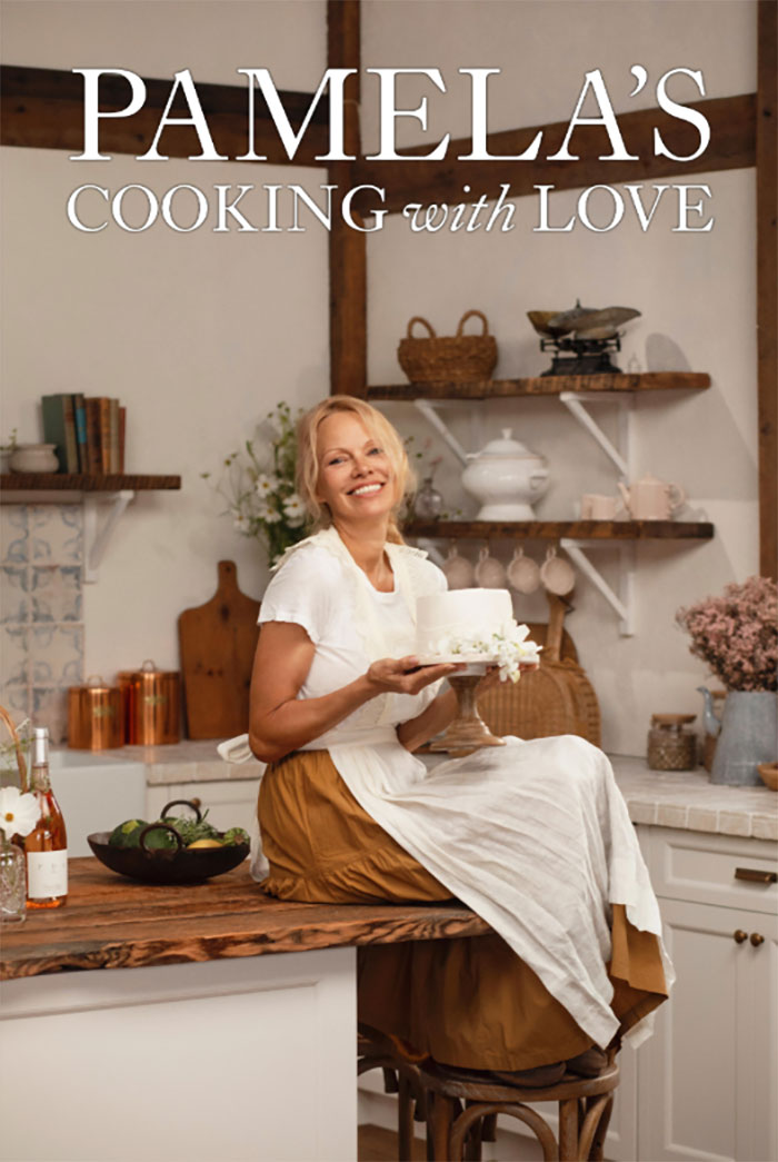Pamela Anderson in kitchen holding a cake, promoting Pamela's cooking show with warm and rustic decor. Pamela Anderson in kitchen holding a cake, promoting Pamela's cooking show with warm and rustic decor.