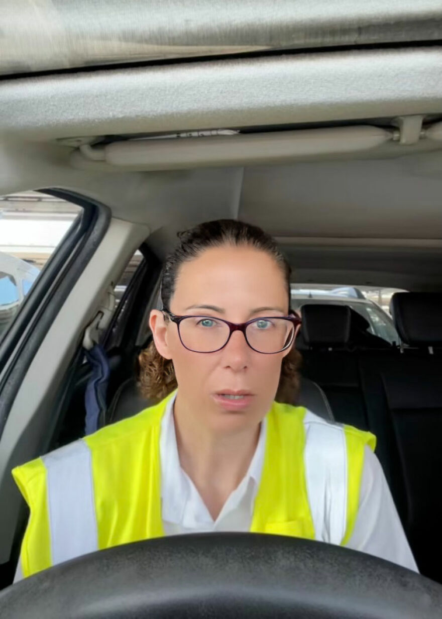 Woman wearing glasses and a high-visibility vest sitting in a car, showing home alone vibes at the airport with a worried expression. Woman wearing glasses and a high-visibility vest sitting in a car, showing home alone vibes at the airport with a worried expression.