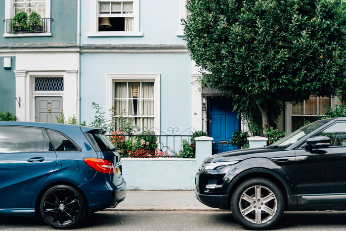 Two cars parked in front of residential houses, illustrating a dodgy neighbor attempting tricking with anonymous notes. Two cars parked in front of residential houses, illustrating a dodgy neighbor attempting tricking with anonymous notes.