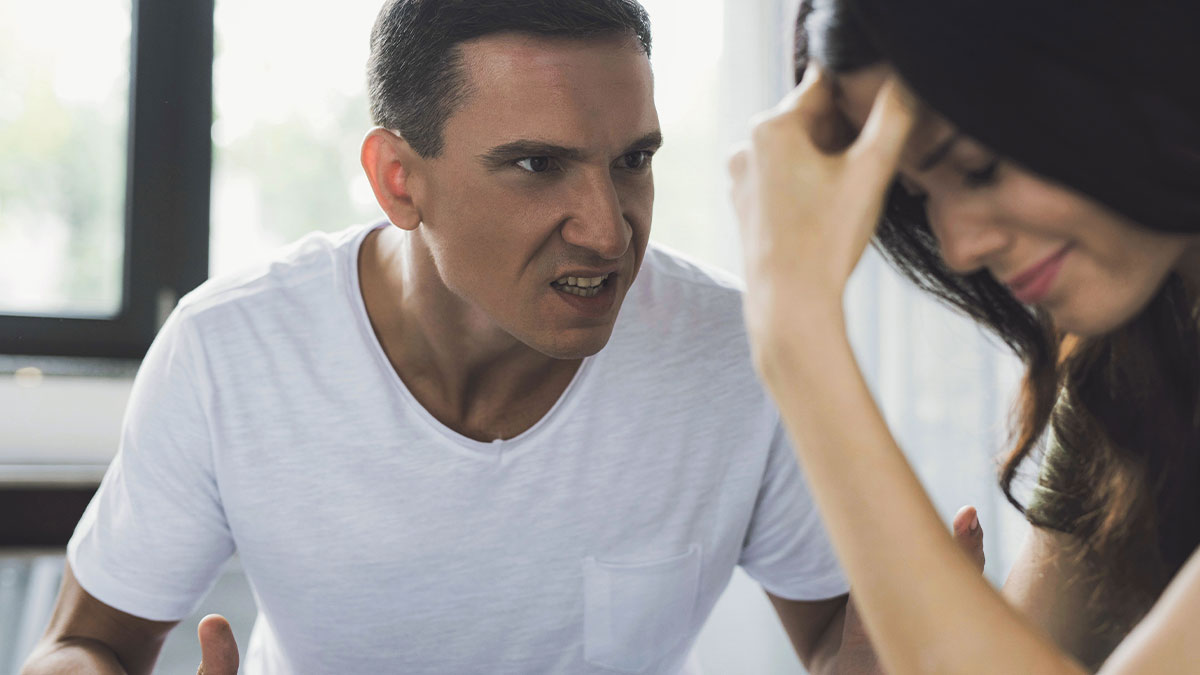 Angry partner scolding heavily pregnant woman who looks distressed and frustrated during a tense moment indoors.