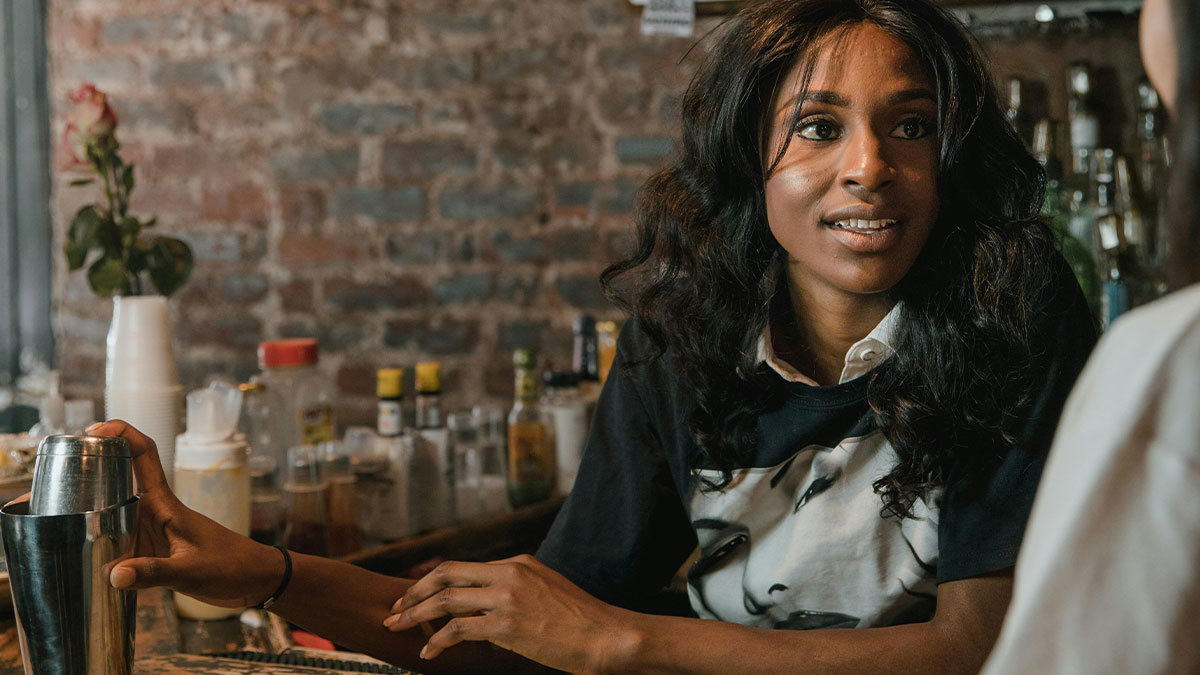 Bar staff engaging with customers in a cozy bar setting, highlighting protection of women from unwanted attention.