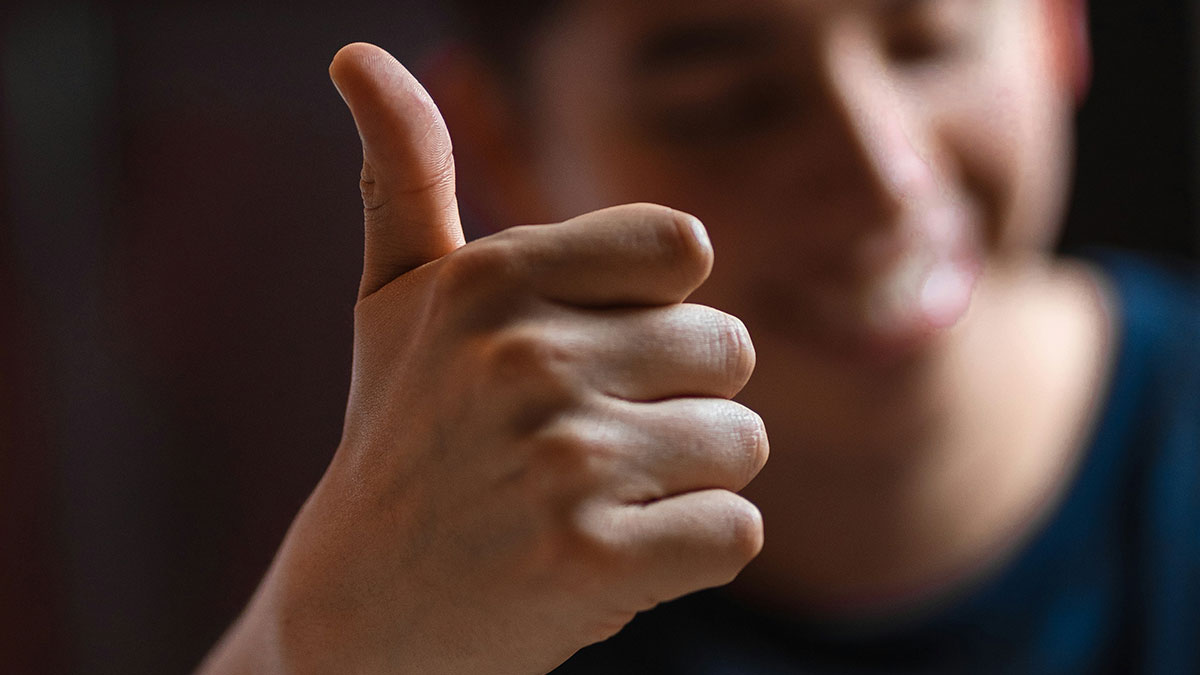 Close-up of hand showing thumbs up gesture symbolizing family flexes confidence and pride.