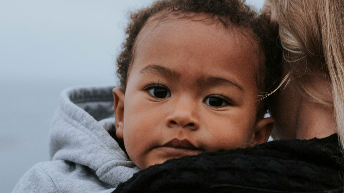 Close-up of a child being held, reflecting themes of personal mysteries and unexplained disappearances.