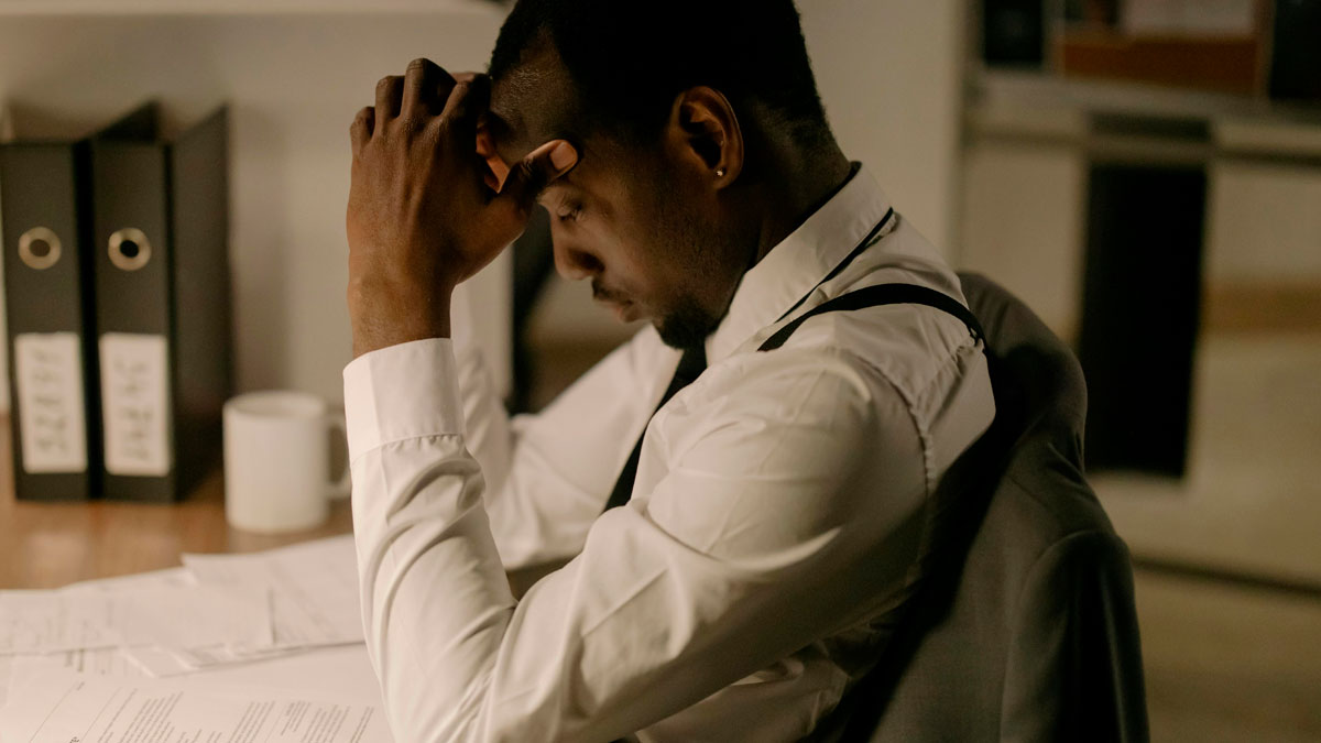 Man in white shirt and suspenders reviewing documents, appearing deep in thought about industry secrets and public insights.