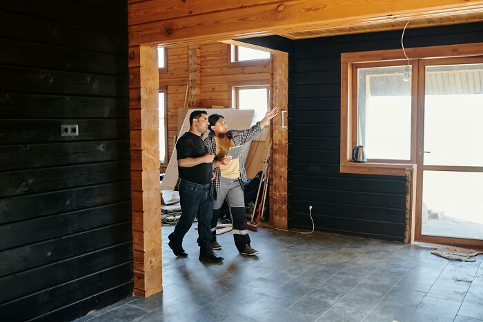Two men inspecting an empty room in a wooden house, a moment people decided f***k this I'm out during renovation.