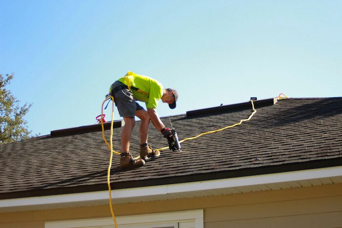 Man in bright shirt working on roof with nail gun, illustrating moments people decided f***k this I'm out.