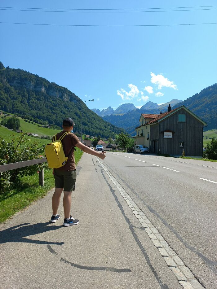 Person with yellow backpack hitchhiking on a mountain road, capturing moments people decided f***k this I'm out.