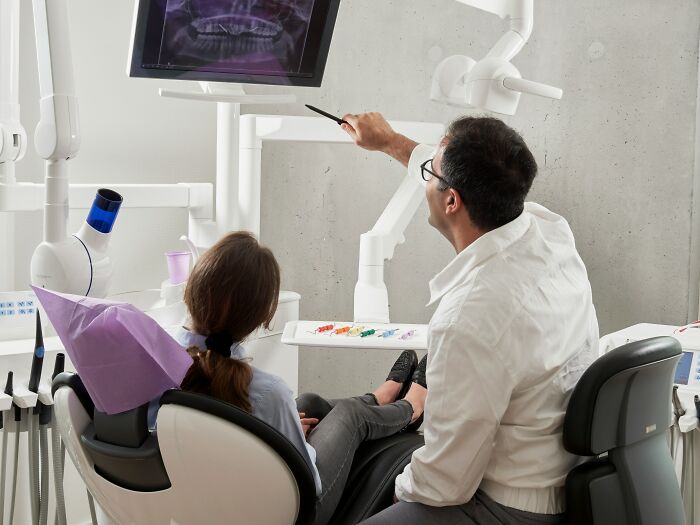 Dentist explaining dental X-ray to patient in clinic, capturing moments people decided f***k this I'm out.