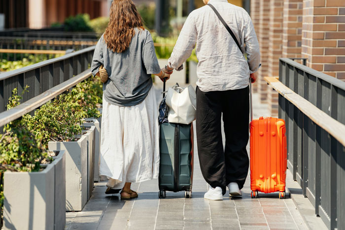 Couple walking with luggage on family vacation, highlighting emotional stress and reactions during travel. Couple walking with luggage on family vacation, highlighting emotional stress and reactions during travel.