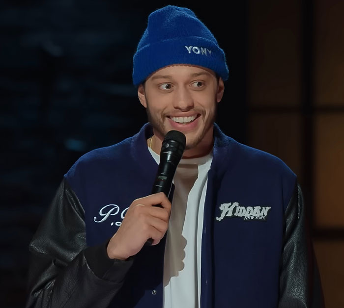 Comedian Pete Davidson on stage holding a microphone, addressing the scrutiny of size of his manhood double standard. Comedian Pete Davidson on stage holding a microphone, addressing the scrutiny of size of his manhood double standard.