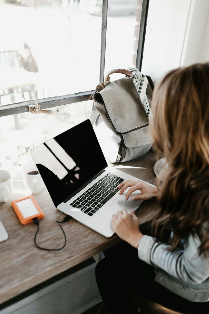 Person working on laptop in a cafe, illustrating PR campaigns and decisions with digital tools and workspace setup.