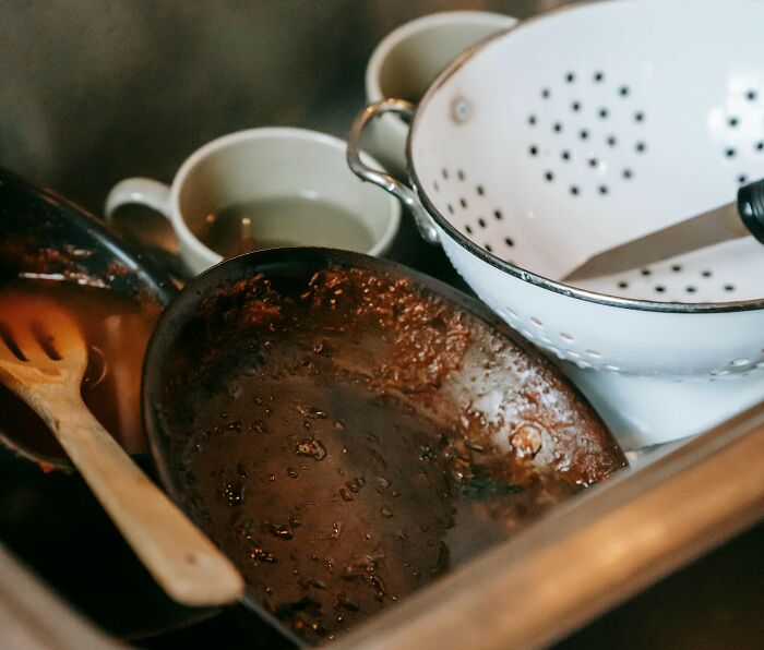 Dirty dishes piled in a kitchen sink, illustrating the grossest and most unexpected things witnessed in strangers' homes.