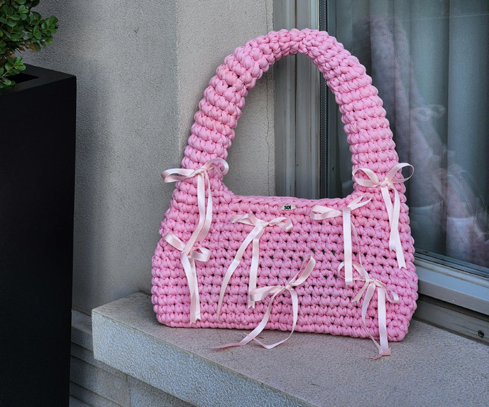 Pink knitted bag with ribbon details placed on a ledge, relating to the story about grieving son and burning bag conflict. Pink knitted bag with ribbon details placed on a ledge, relating to the story about grieving son and burning bag conflict.