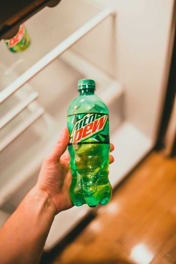Hand holding a Mountain Dew bottle in front of an open fridge, illustrating PR campaigns and decisions fails.