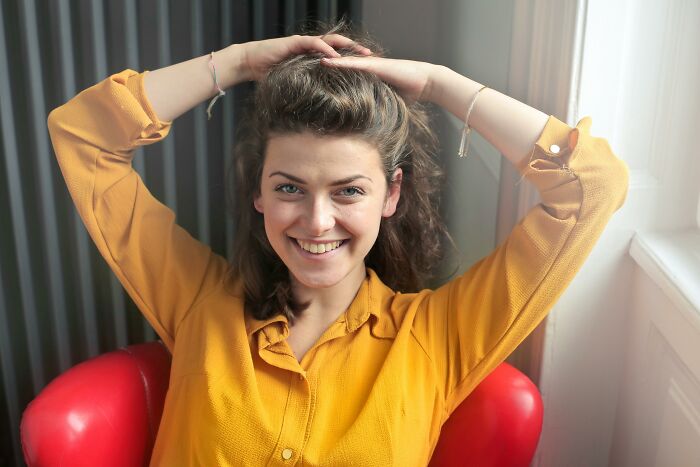 Young woman smiling and relaxing in a red chair, symbolizing the superpowers of picking the wrong line at the grocery store.