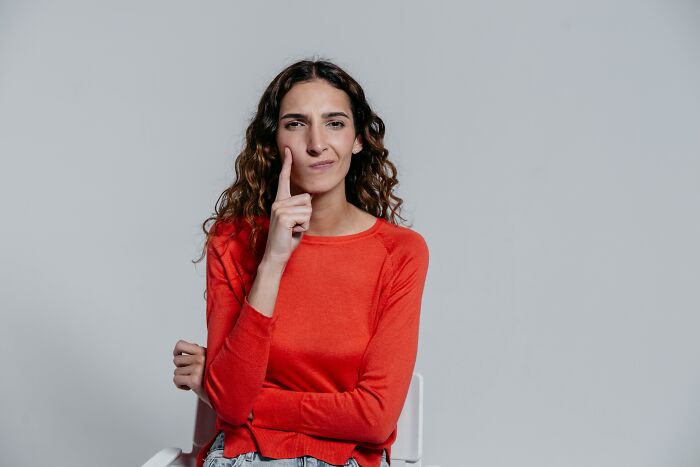 Young woman in a red sweater sitting thoughtfully, trying to type challenging words without a spelling mistake. Young woman in a red sweater sitting thoughtfully, trying to type challenging words without a spelling mistake.