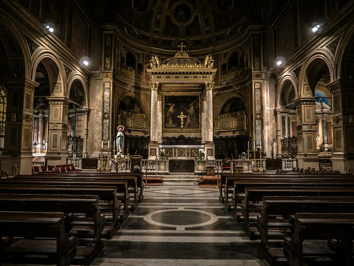 Interior of an ornate church with wooden benches and a decorative altar highlighting performative behaviors in society.