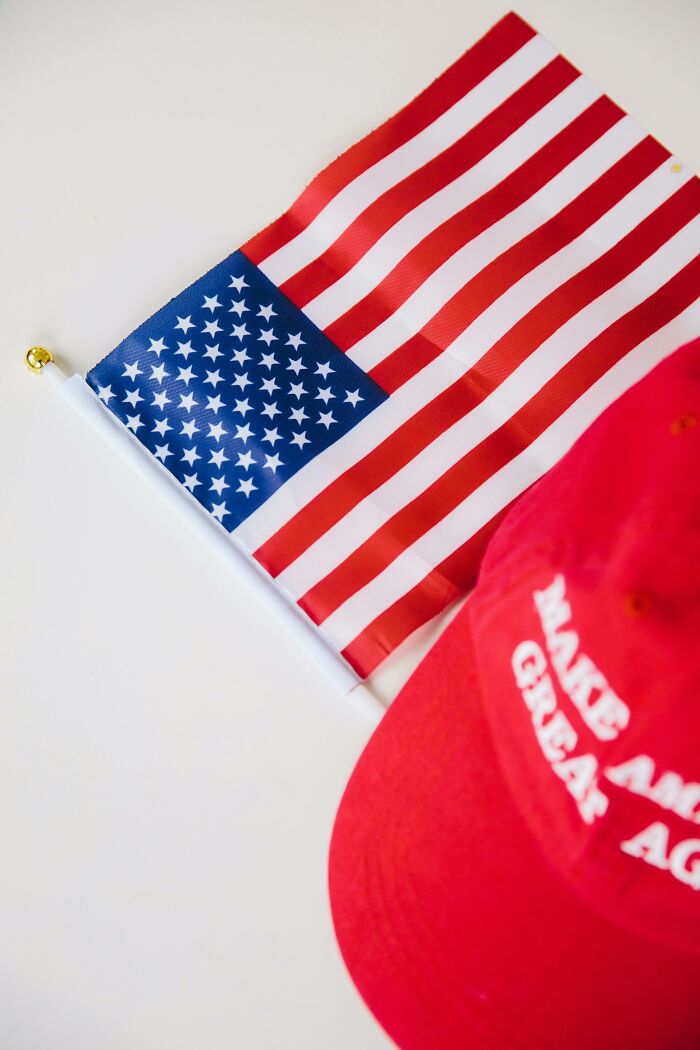American flag next to a red cap, illustrating performative behaviors and societal attitudes in the United States.