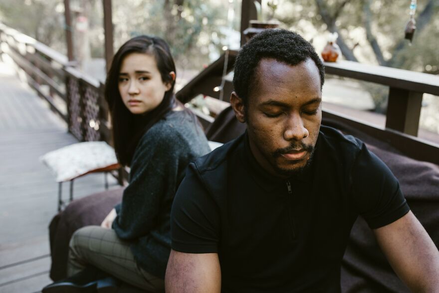 A conflicted couple sitting apart on a wooden bench outdoors, showing emotional tension and soul ties strain. A conflicted couple sitting apart on a wooden bench outdoors, showing emotional tension and soul ties strain.