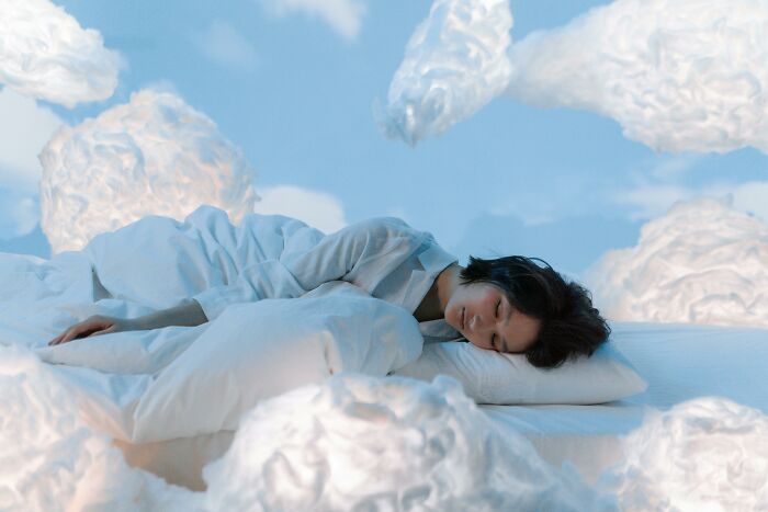 Person lying on a bed surrounded by clouds, illustrating the feeling of picking the wrong line at the grocery store.
