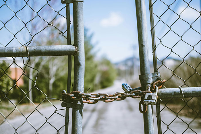 Chain and padlock securing a metal gate blocking the road, symbolizing restriction or threat involving young woman and cops. Chain and padlock securing a metal gate blocking the road, symbolizing restriction or threat involving young woman and cops.