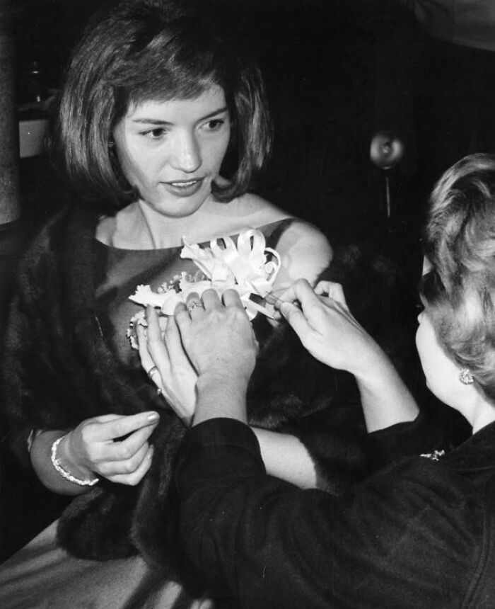Young LA woman dressed elegantly with a fur shawl having a floral corsage pinned on her in 1962.