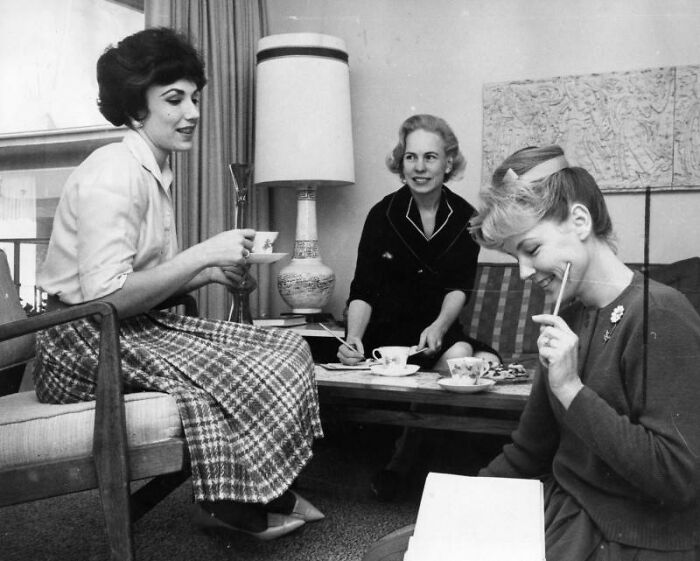 Three LA women enjoying tea and conversation in a cozy 1960s living room, capturing vintage lifestyle moments.