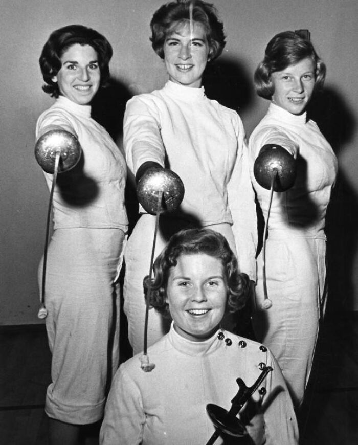 Four LA women fencers posing with their foils, dressed in white fencing uniforms, showcasing 1960s athletic style.