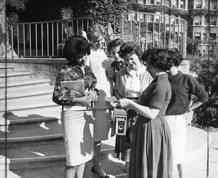 Group of LA women in 1962 gathered outdoors, smiling and sharing moments, capturing life with a vintage camera.