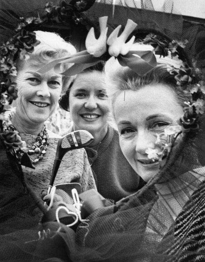 Three LA women smiling and posing with golf clubs and floral accessories in a candid 1962 lifestyle moment.