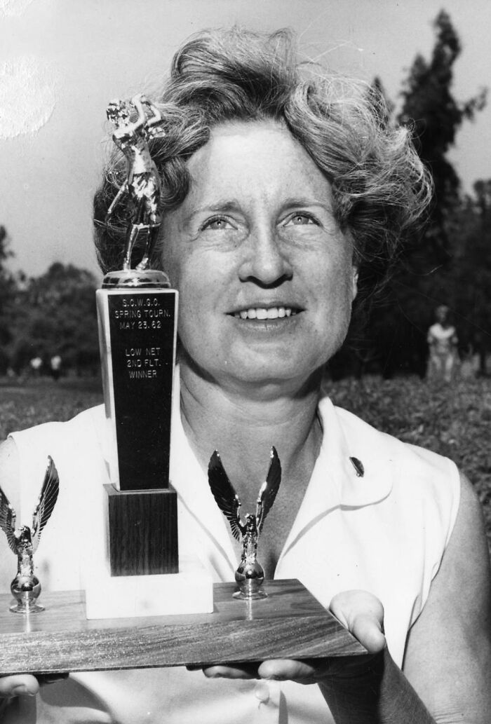 Woman from LA holding a golf trophy, smiling outdoors, representing LA women living their best lives in 1962.