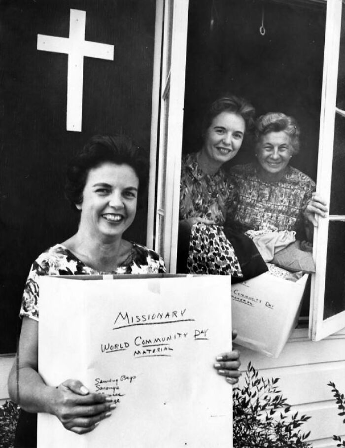 Three LA women smiling while holding boxes of missionary and community day material in 1962 black and white photo.