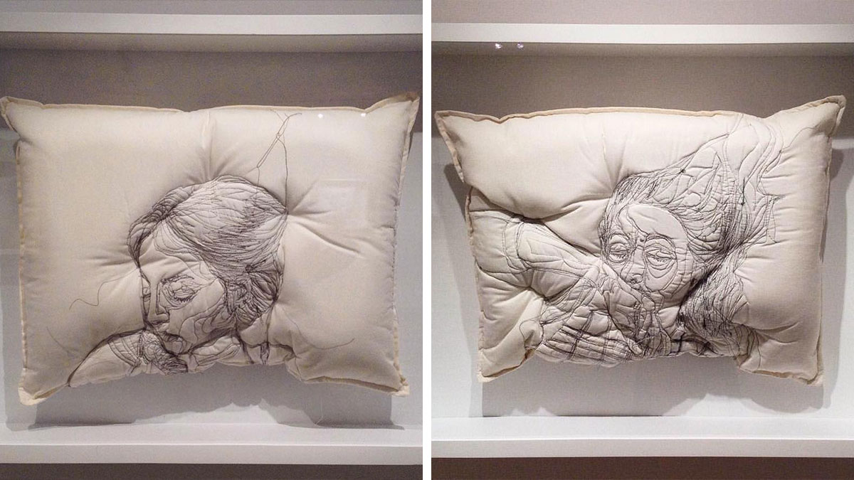 Two embroidered pillows by Maryam Ashkanian featuring detailed line art faces, capturing a dreamy and serene sleep theme.