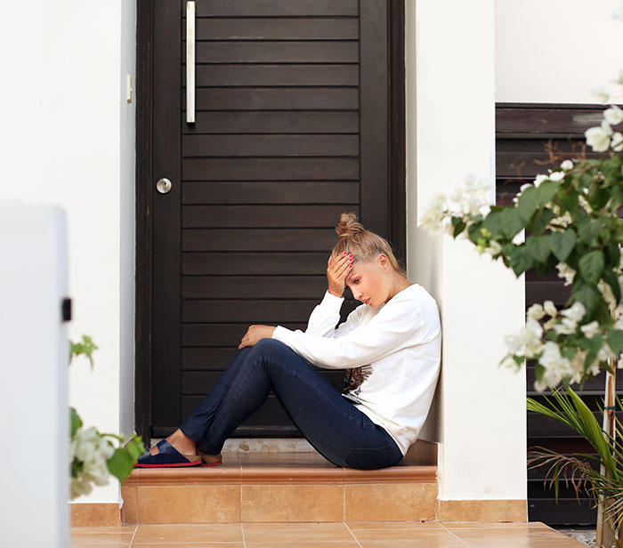 Woman sitting on porch steps upset after catching husband cheating, neighbor witnessing shocking confrontation outdoors.